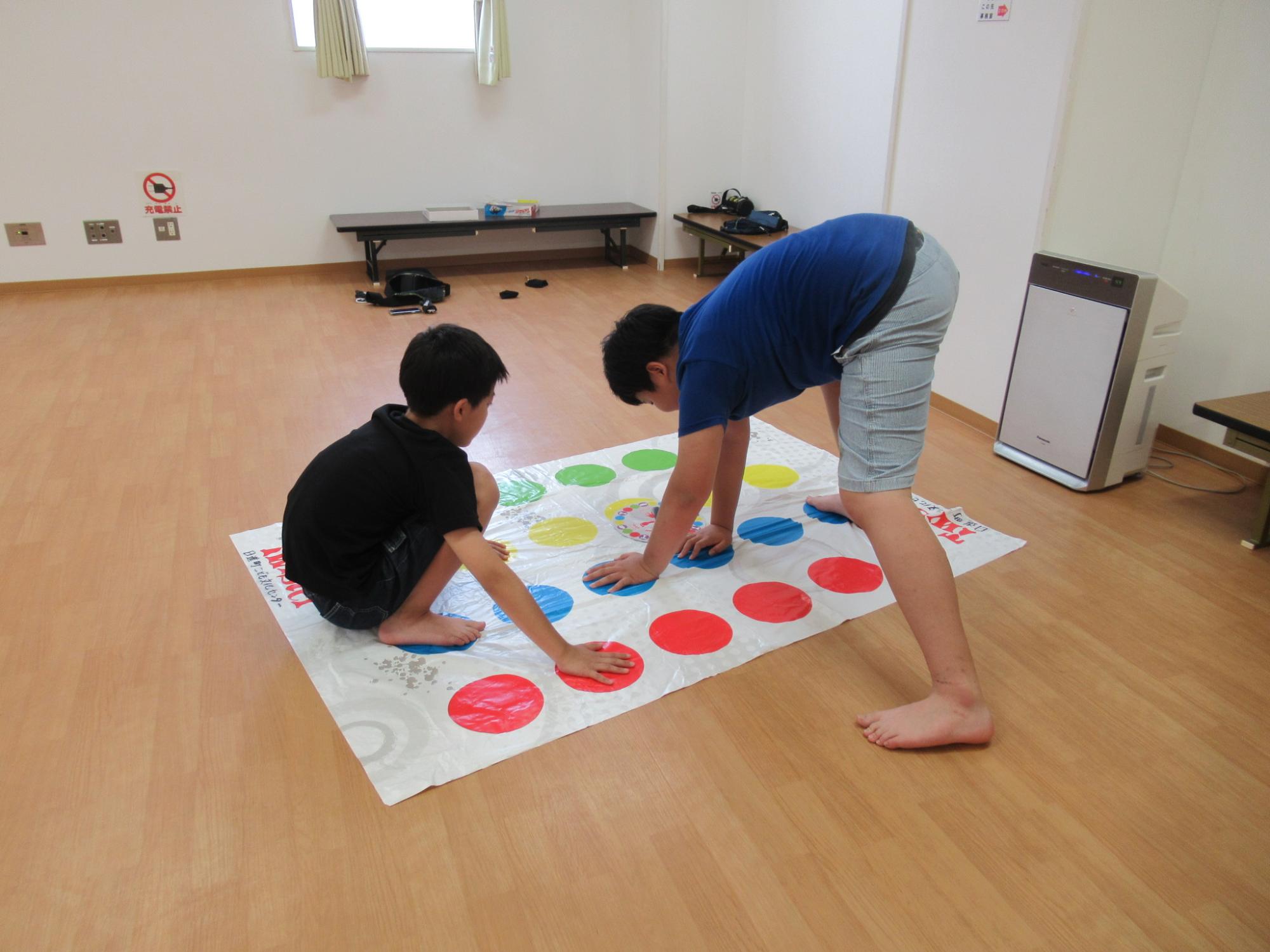 小学生がツイスターで遊んでいる様子の写真