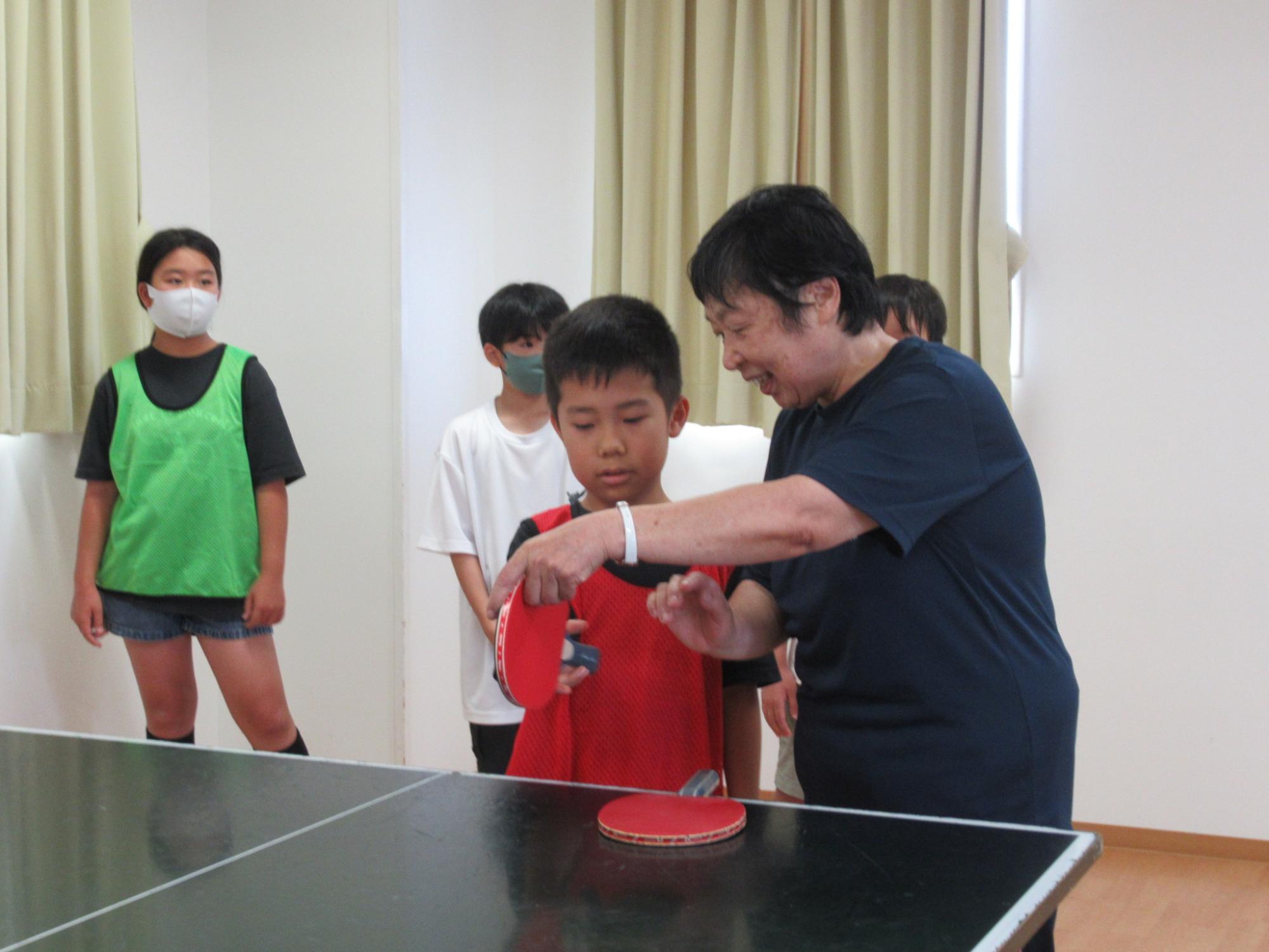 卓球交流会にてラケットの持ち方を教わっている子どもの写真