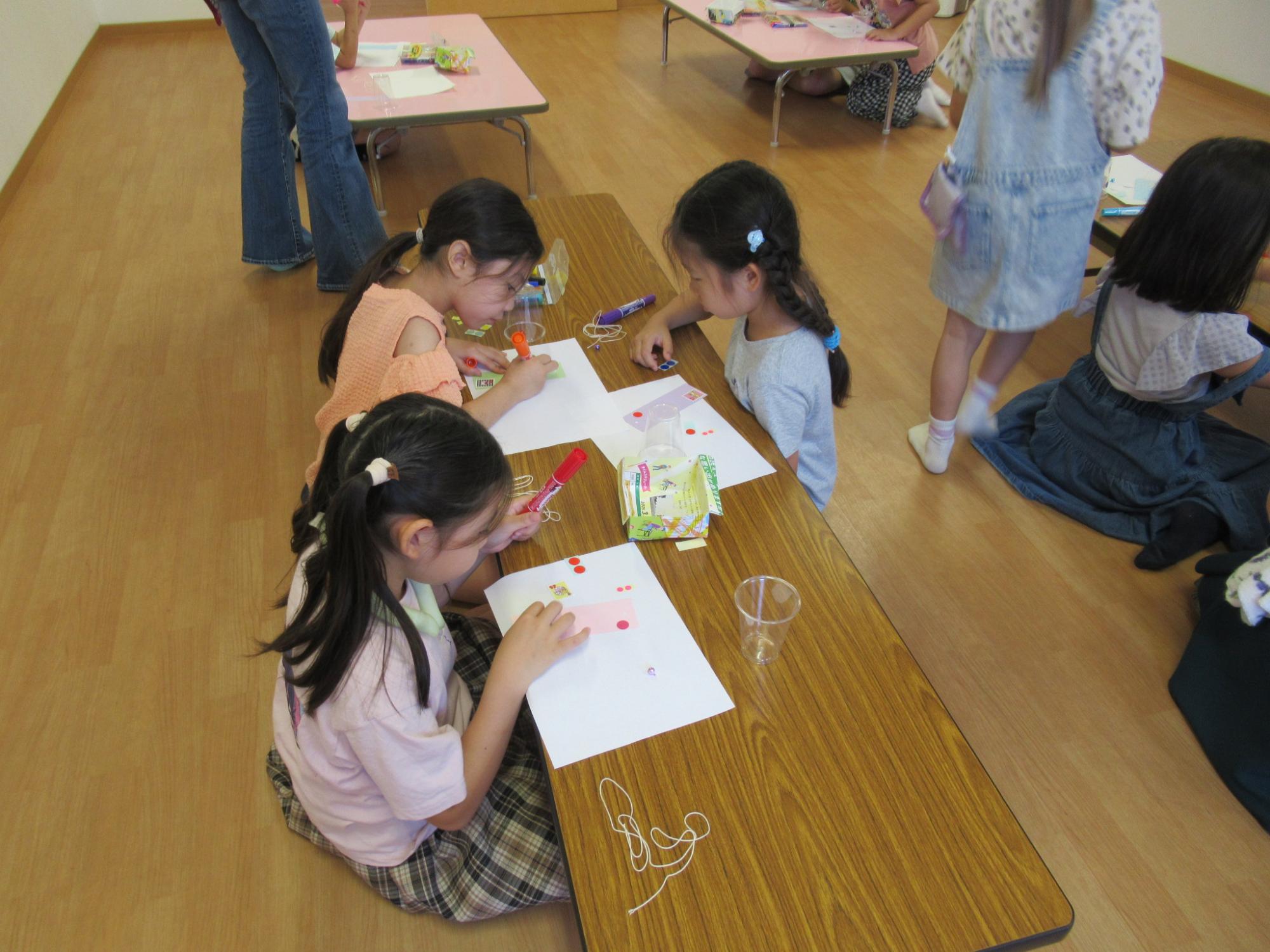 風鈴作りにて短冊にデコレーションしている子どもたちの写真
