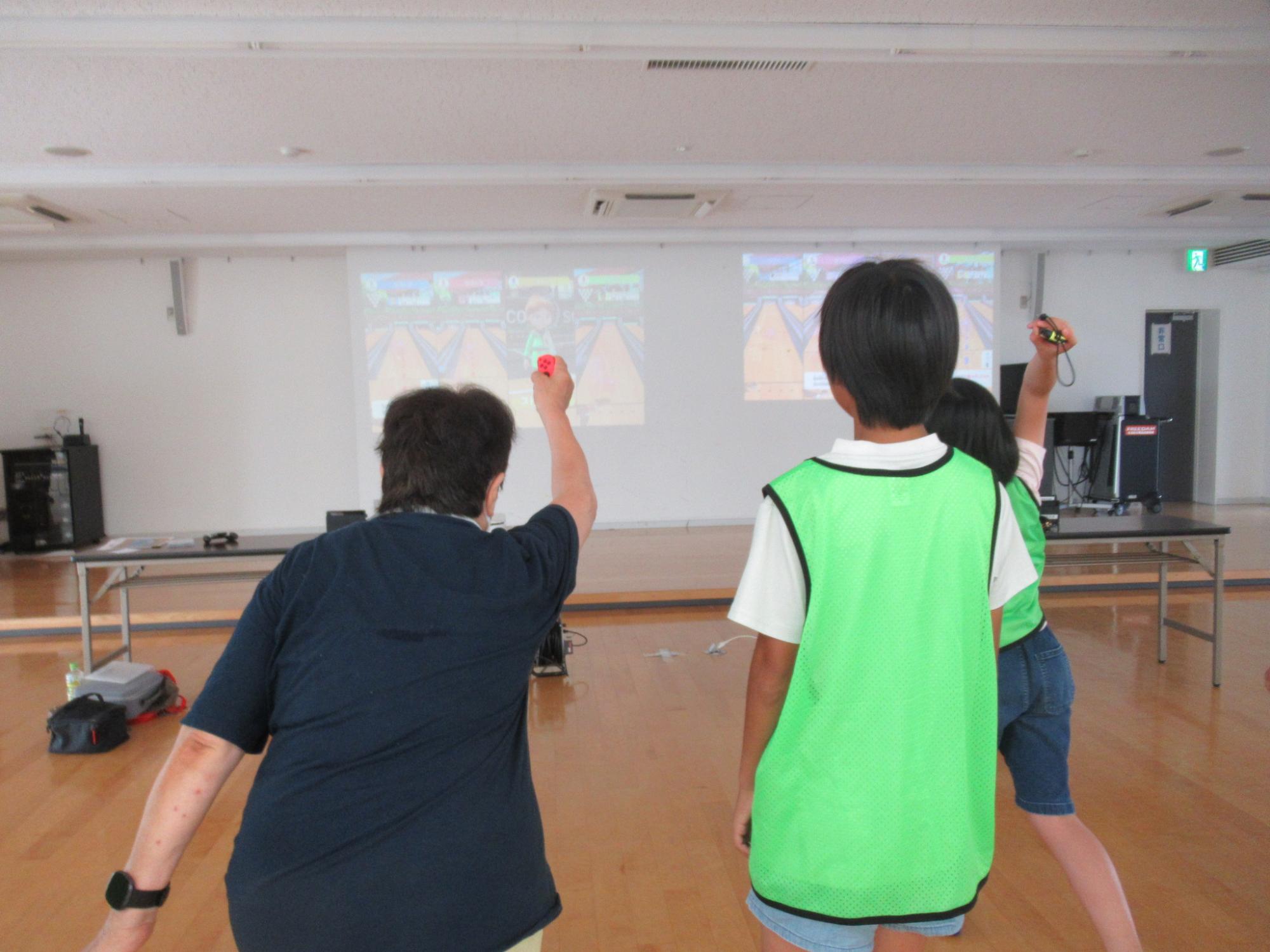 ボウリングゲームを楽しむ老人と小学生の写真