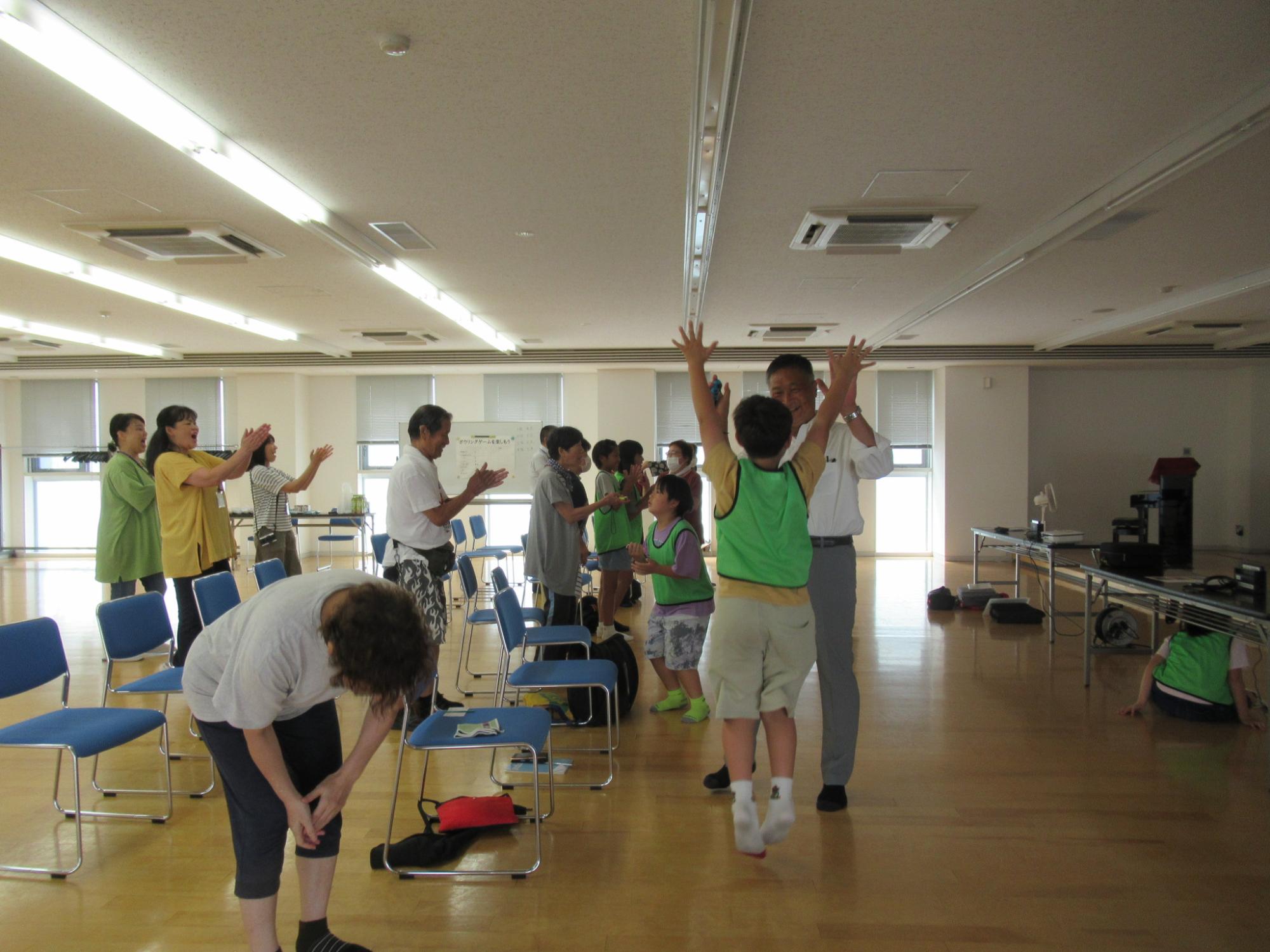 ボウリングゲームでストライクを出し、ハイタッチして喜びを分かち合う老人と小学生の写真