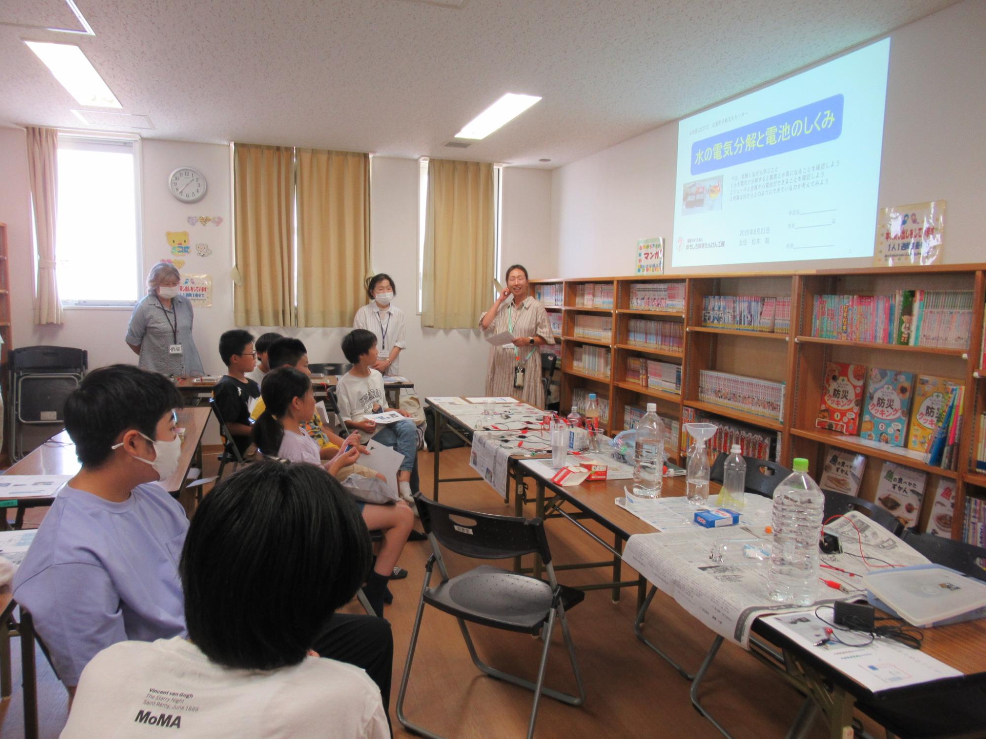 水の電気分解と電池のしくみについて座学を聞いている子どもたちの写真