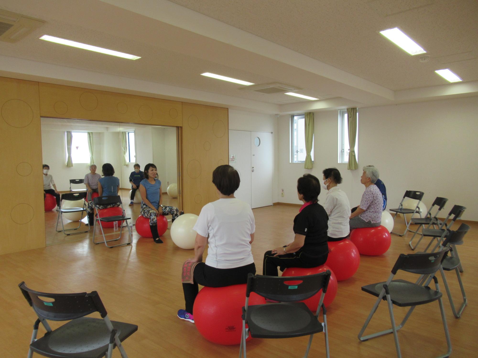 バランスボールエクササイズにて講師の話を聞く様子の写真