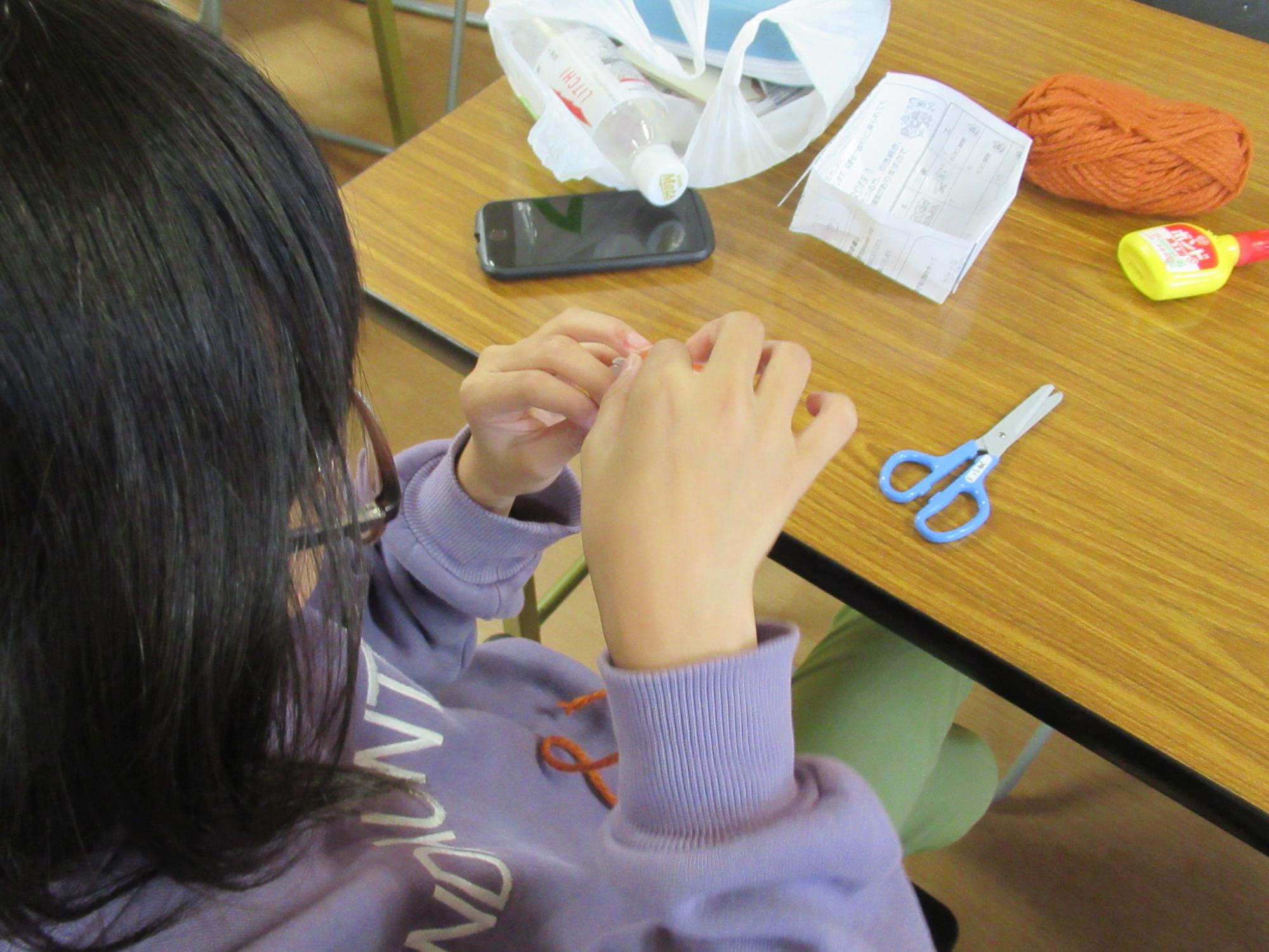 毛糸を使ってハロウィンの工作をしている小学生の写真