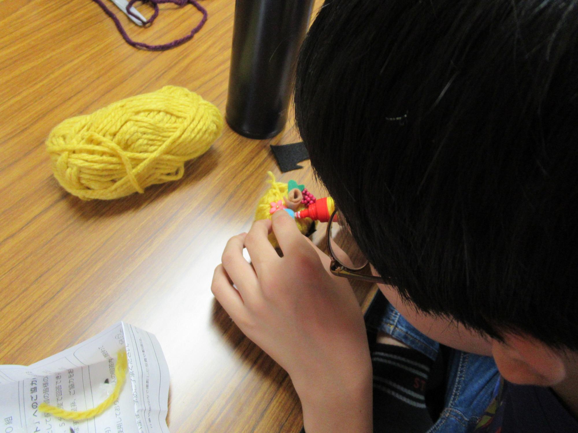 毛糸を使ってハロウィンの工作をしている小学生の写真