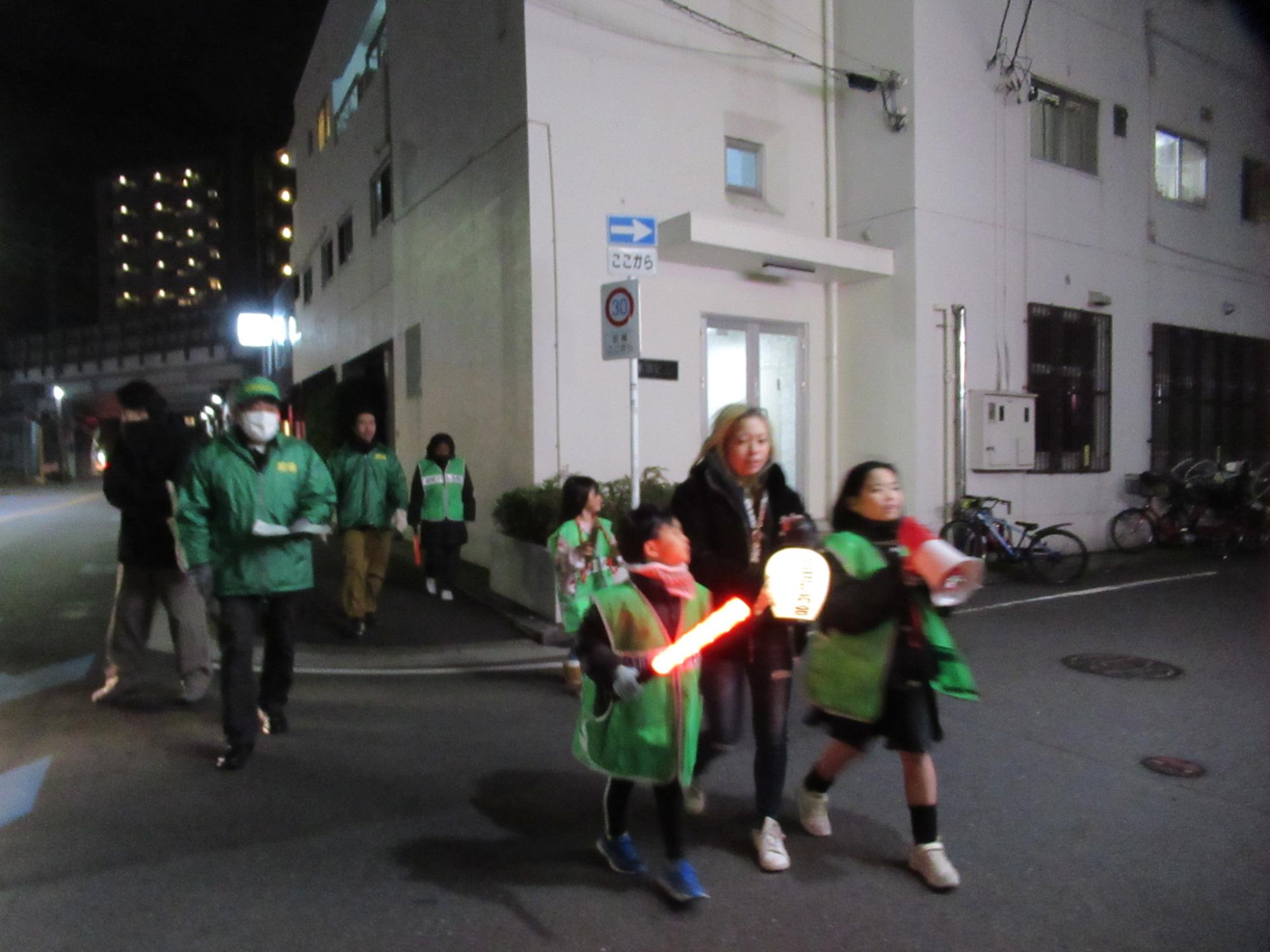 拍子木を鳴らしながら火の用心を地域へ呼びかける子どもたちと成人の写真