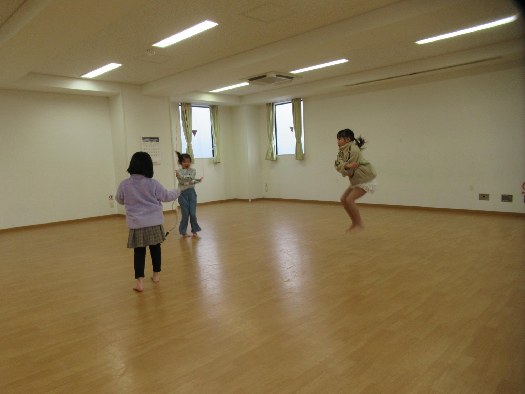 3人組の子どもたちが縄跳びを楽しんでいる写真