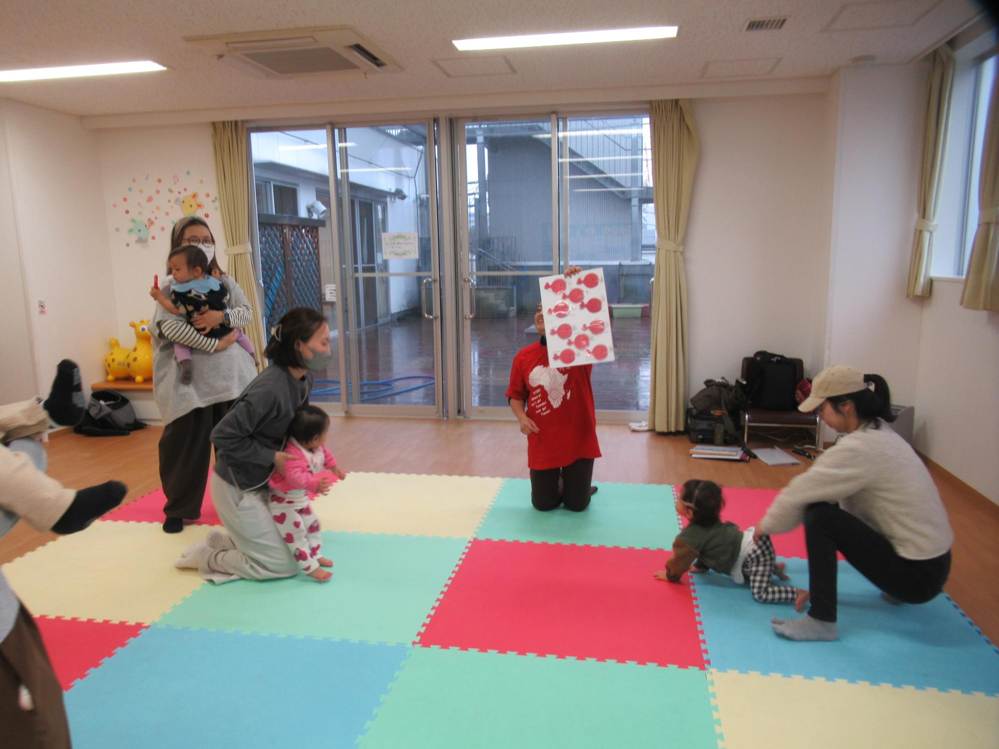 多言語リトミックを楽しんでいる乳幼児親子と講師の写真