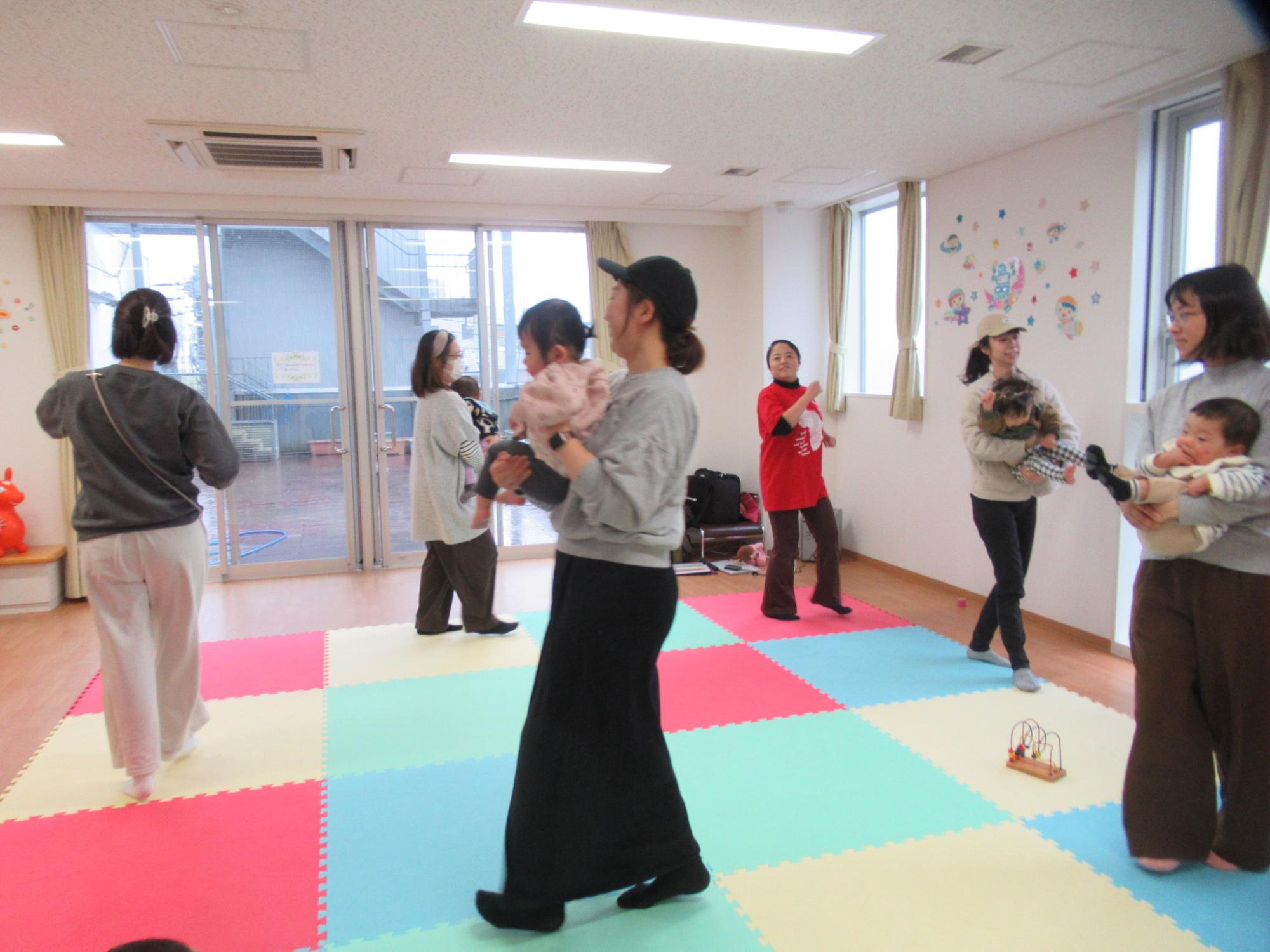 多言語リトミックを楽しんでいる乳幼児親子と講師の写真