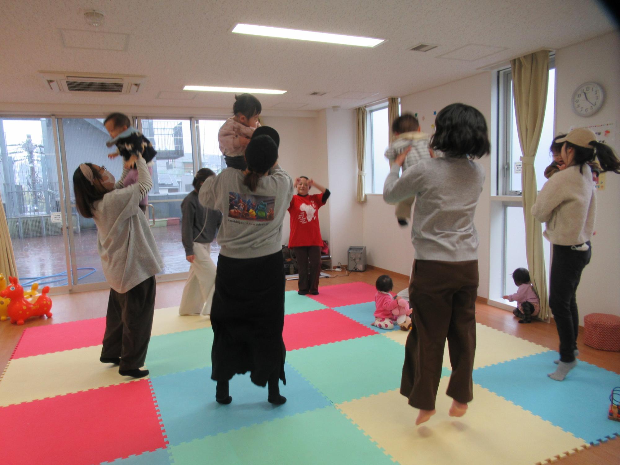 多言語リトミックを楽しんでいる乳幼児親子と講師の写真