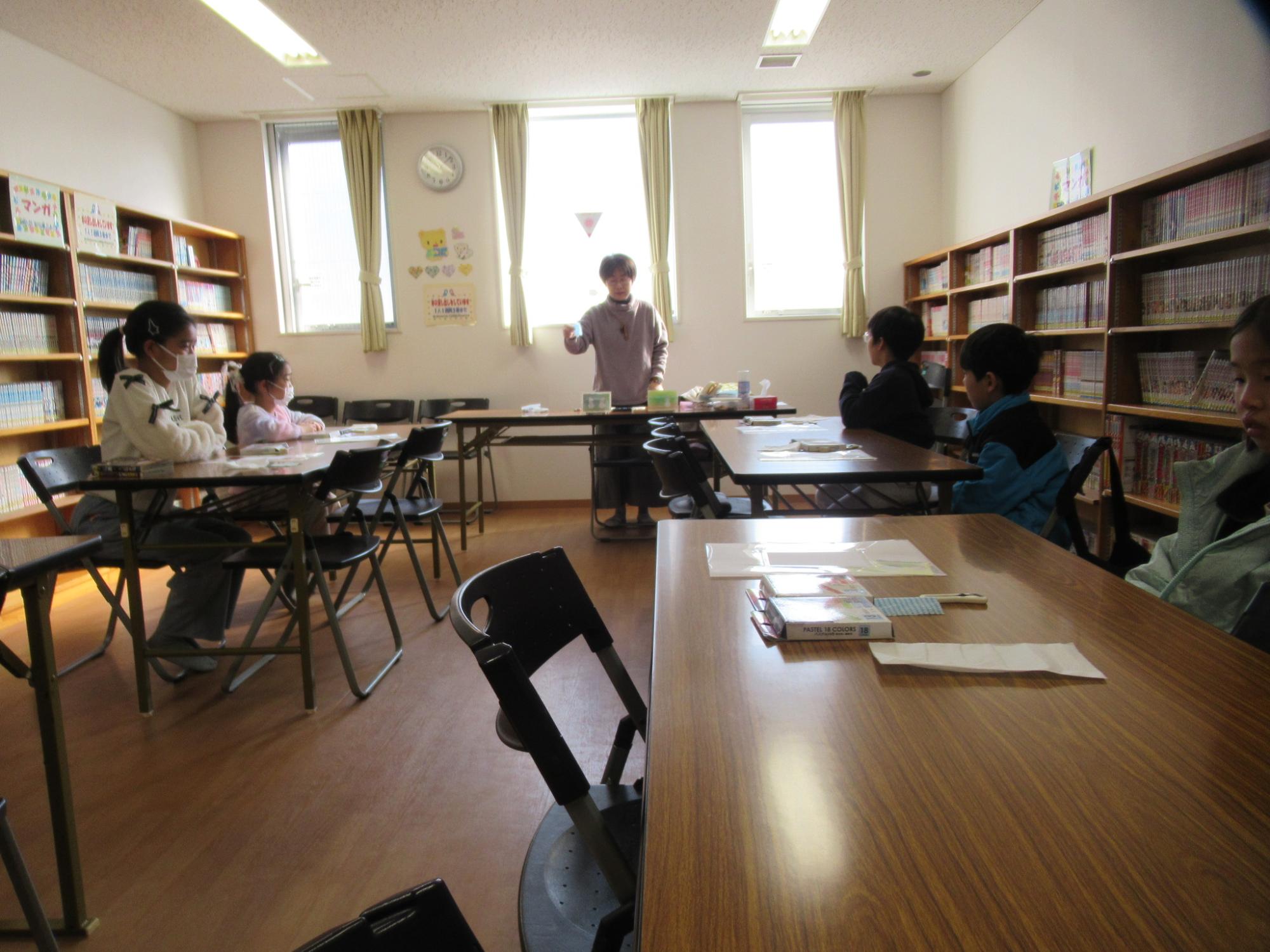 パステルアートの説明を聞いている子どもたちの写真