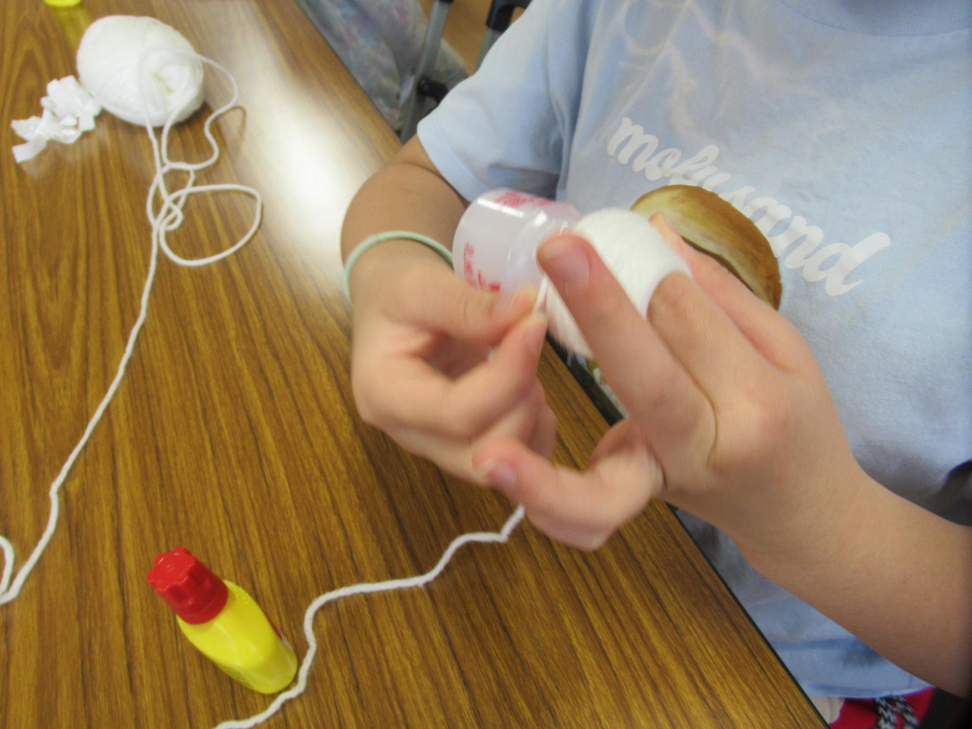 空き容器に毛糸を巻き付けている子どもの様子の写真