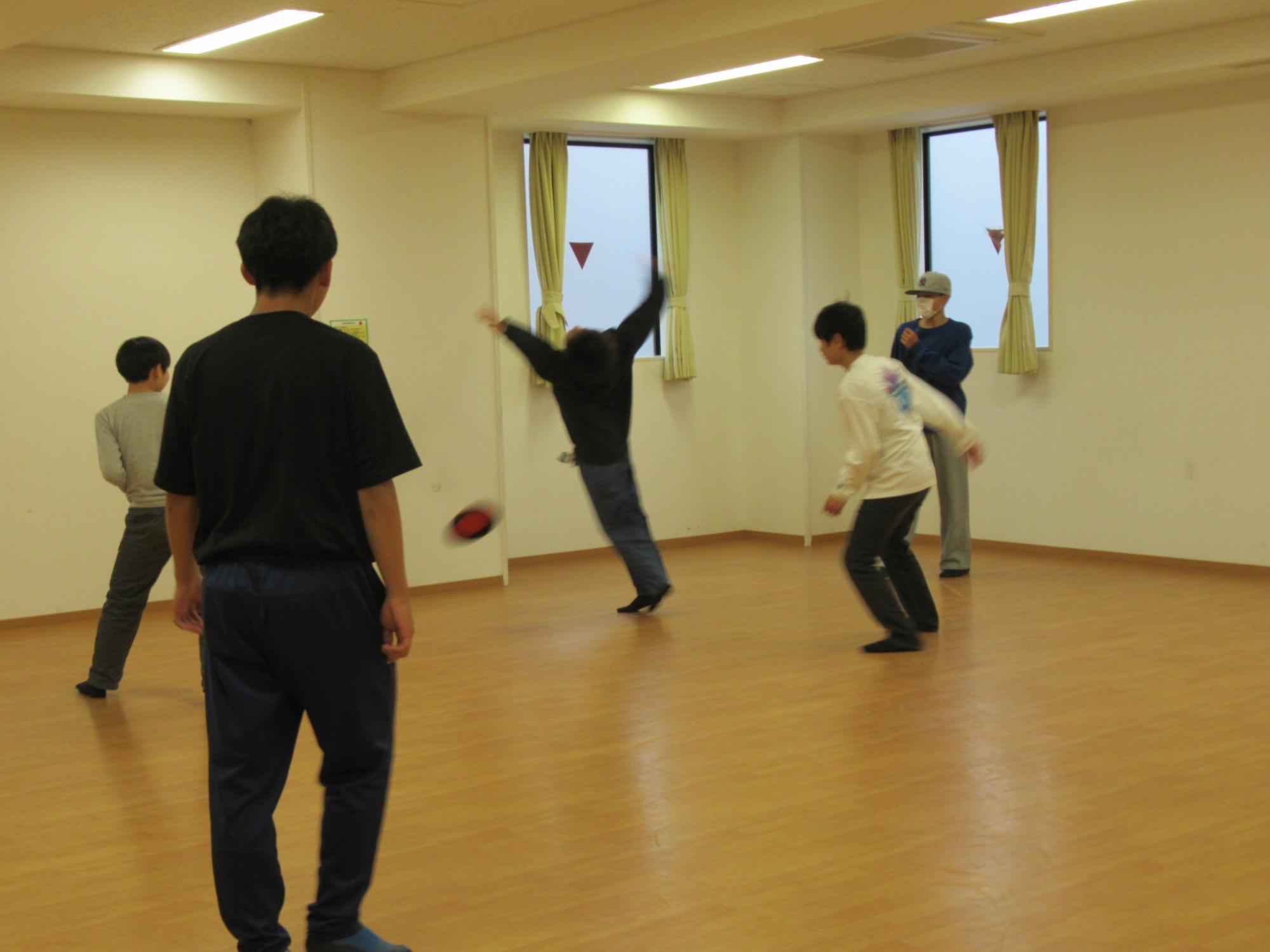 集会室でフリスビーを楽しむ男子中学生グループの写真