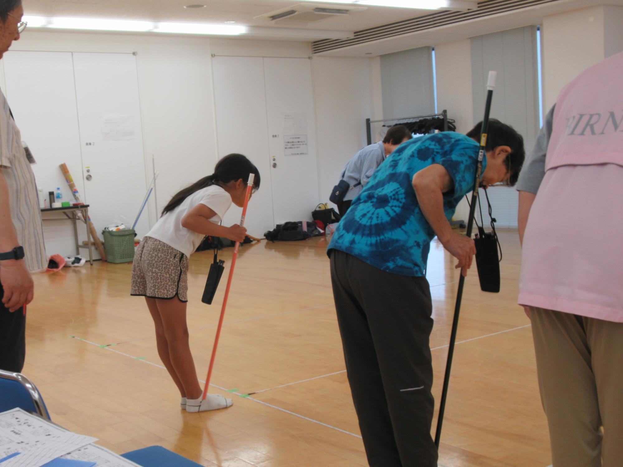 作法を学びながら吹矢を楽しむ老人と小学生の写真