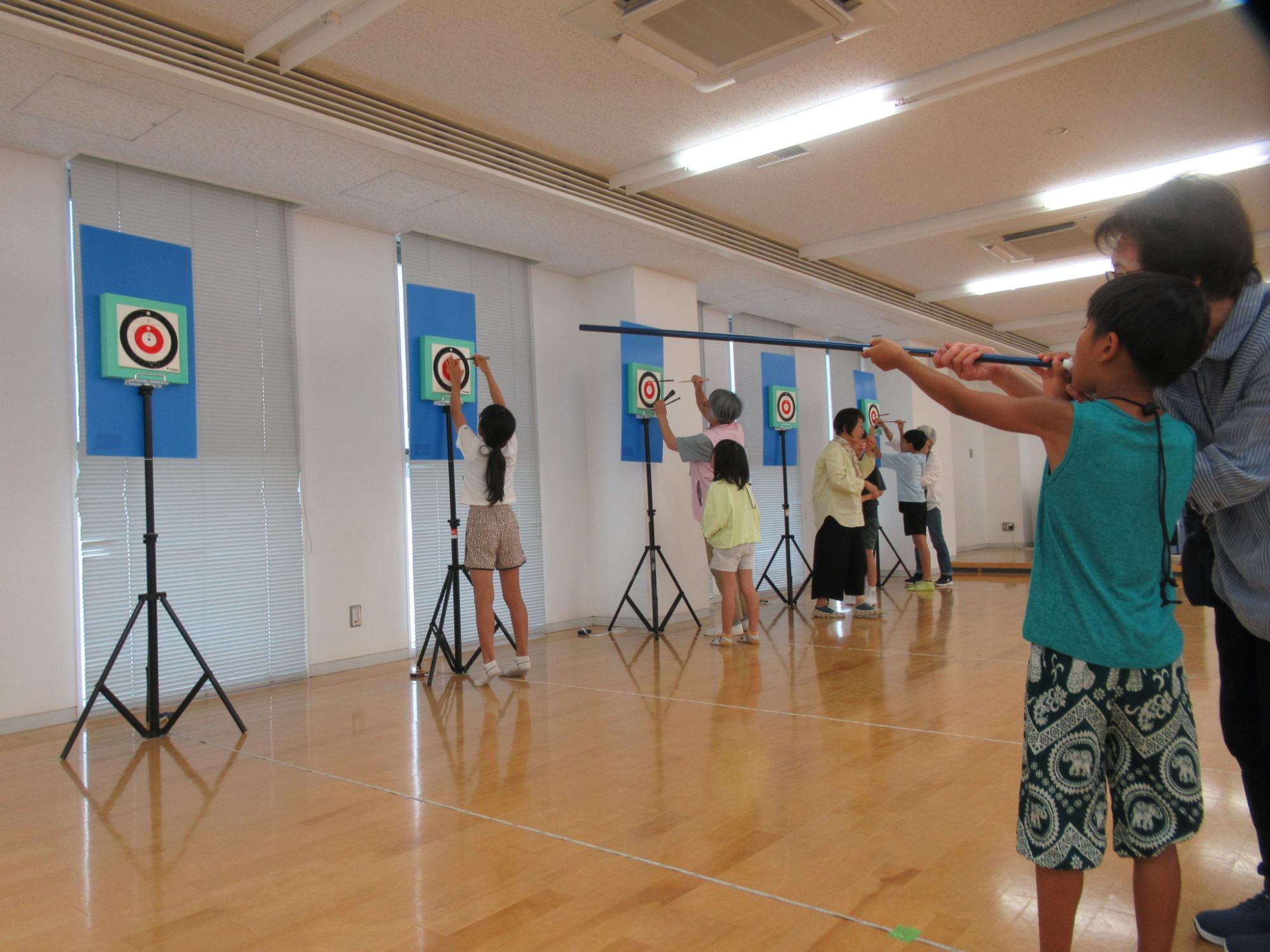 吹矢を楽しむ老人と小学生の写真