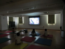 スクリーンからの光だけが灯る暗い部屋で映画鑑賞をする子供たちの写真