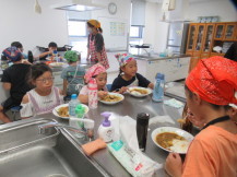完成したカレーをみんなで一緒に食べている子供たちの写真