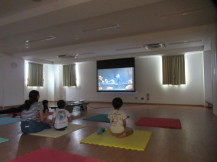 暗くした部屋の前方に設置されたスクリーンに映画が映し出されている写真