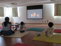 床に座って映画を見ている二人の子供と母親の写真