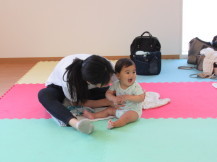 満面の笑みの乳幼児を同じ目線で見ている母親の写真