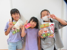 3人の女の子が景品を持ってピースサインで撮影している写真