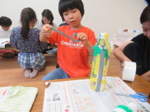 ペットボトルにテープでデコレーションしていく男の子を撮影した写真