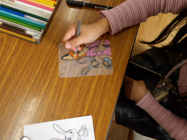 プラバンの上からイラストをペンでなぞる小学生の写真