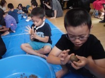 1人のメガネをかけた男の子が必死に泥団子を丸めている様子を写した写真
