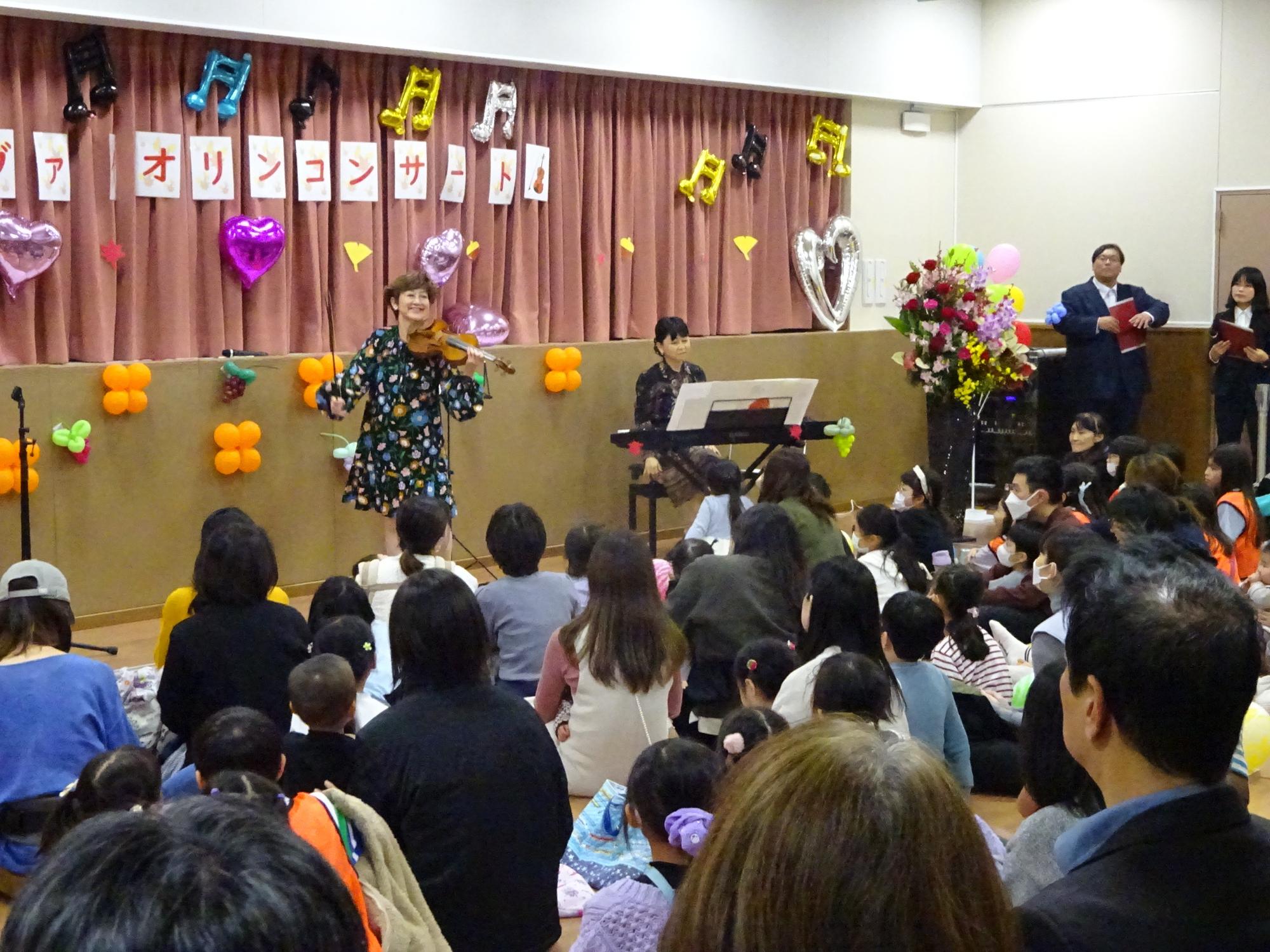 小杉こども文化センターにて、ヴァイオリンの演奏をしている大谷康子氏とその演奏を聞く参加者の写真