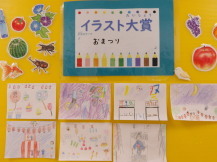 壁に「イラスト大賞」と書かれた紙が貼られその下に7枚のイラストが展示されている写真