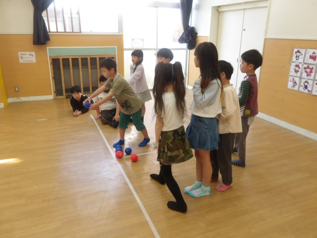2チームにわかれてボッチャの試合をし、男子小学生がボールを投げようとしている写真