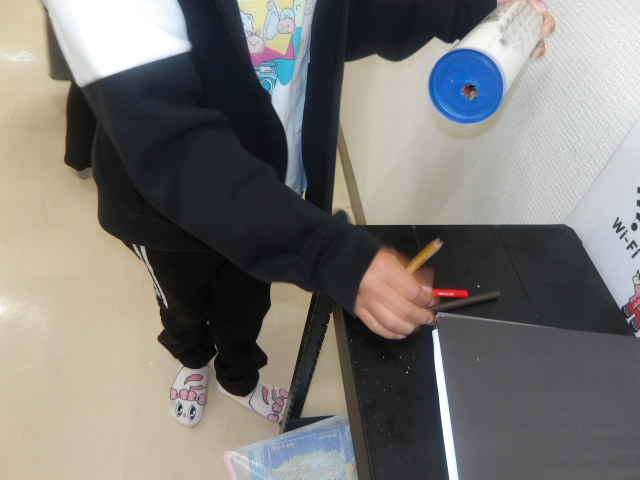 筒に入れた色鉛筆をおみくじのように3本出す小学生の写真