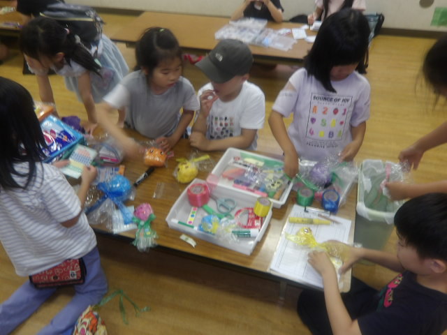 てるてるぼうずに使うシールやペンを選んでいる小学生達の写真