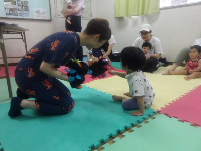 パペットを持って説明をする講師と興味深々な幼児さんの写真