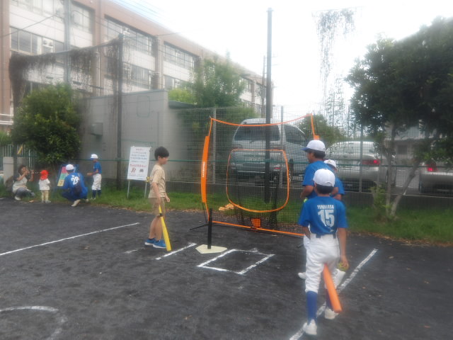 地域団体が出店しているティーバッティングに挑戦する子どもの写真