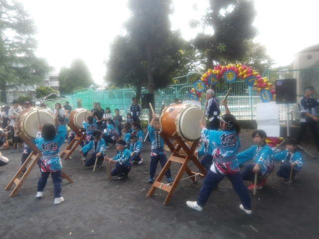 平間公園に設置した舞台で和太鼓を発表する地域の人と子ども達の写真