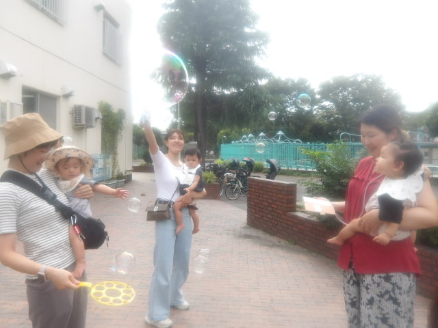 お母さんたちが飛ばしたシャボン玉を見つめる幼児たちの写真