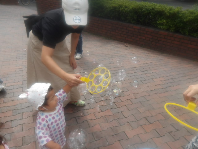 お母さんと一緒にシャボン玉を楽しむ幼児の写真