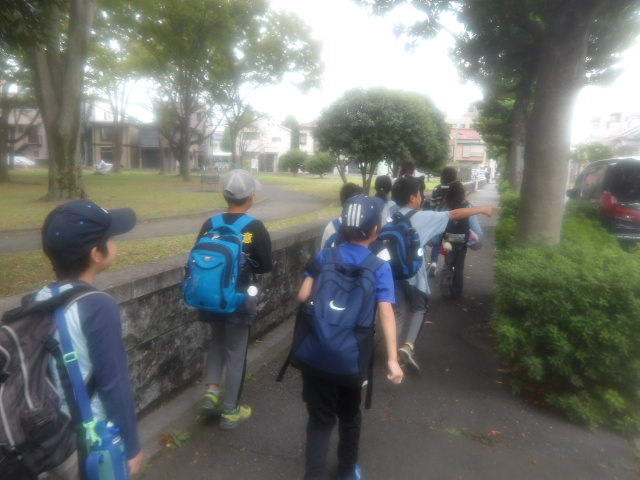 歩道を歩きながらバス乗り場に向かう子供達の写真