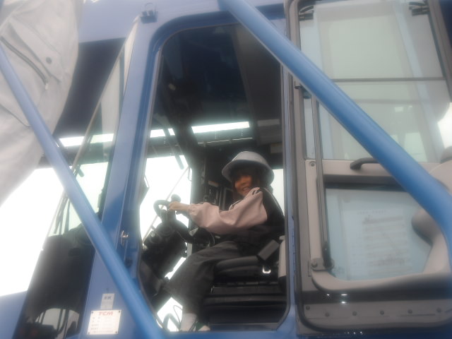 クレーン車に乗り、ハンドルを握っている女子小学生の写真