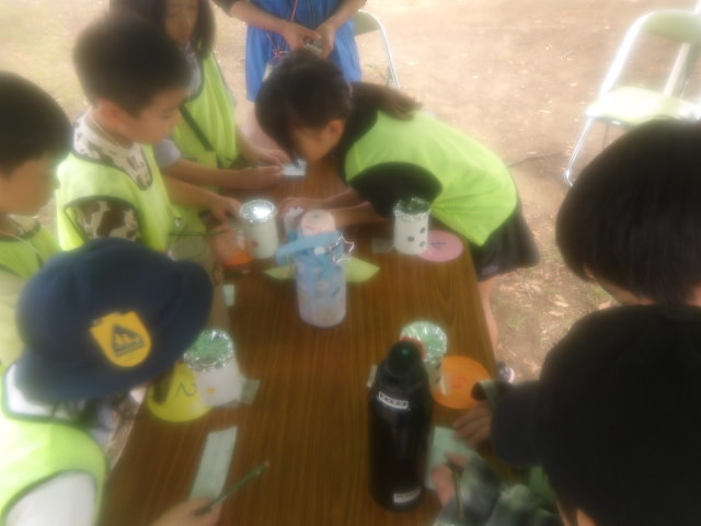 プラコップの中に入っている調味料の食べ物を当てるゲームに挑戦する子供達の写真。