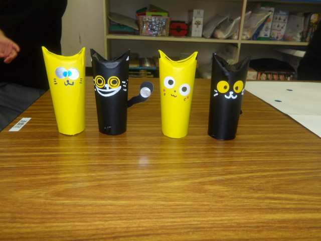 トイレットペーパーの芯に黒や黄色の折り紙を貼って作った猫の写真