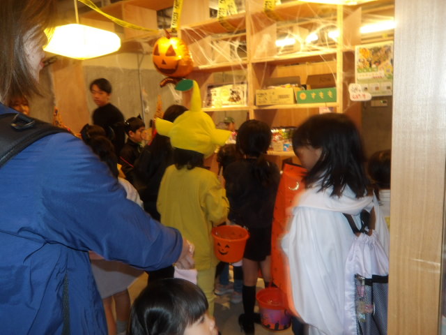 平間商店街にある駄可笑屋敷の店員からお菓子をもらう子供達の写真