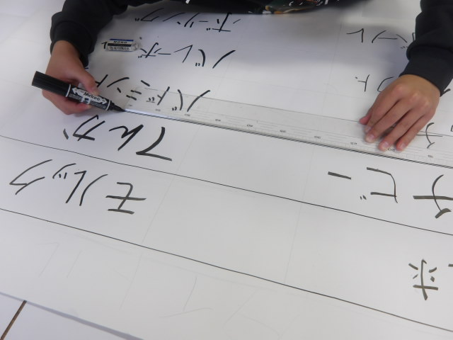 色紙に書き出したやりたいスポーツを大きい模造紙に書いていき、大きいアンケート表を作る男子小学生の写真