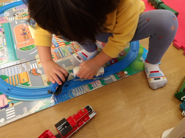 プラレールの電車を連結させる幼児の写真