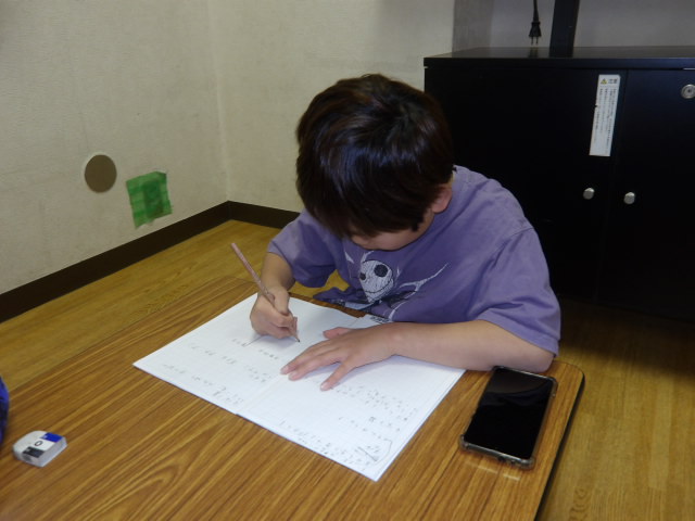 1月21日に開催するドッジボール大会の景品を、ノートに書いていく小学生男子の写真