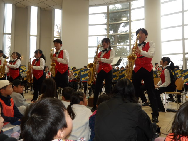 高校生達のサックスの演奏を聴く参加者達の写真