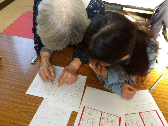 先生に硬筆の作品を見てもらう小学生の写真