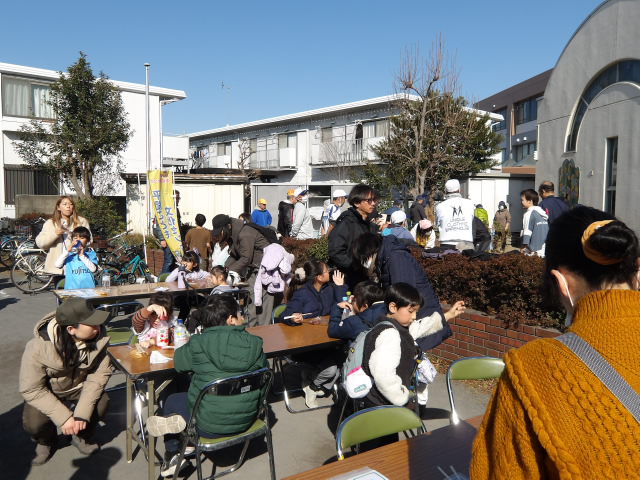 外の飲食スペースでおもちを食べながら過ごす参加者達の写真