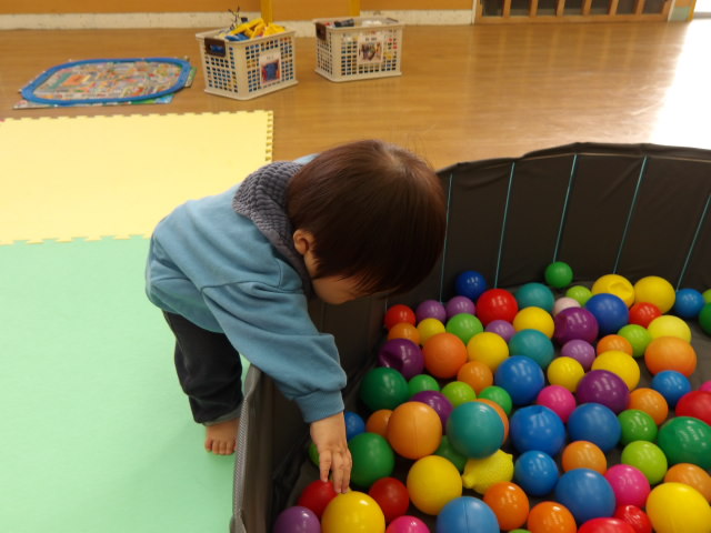 ボールプールの中にあるボールを取ろうとする幼児の写真